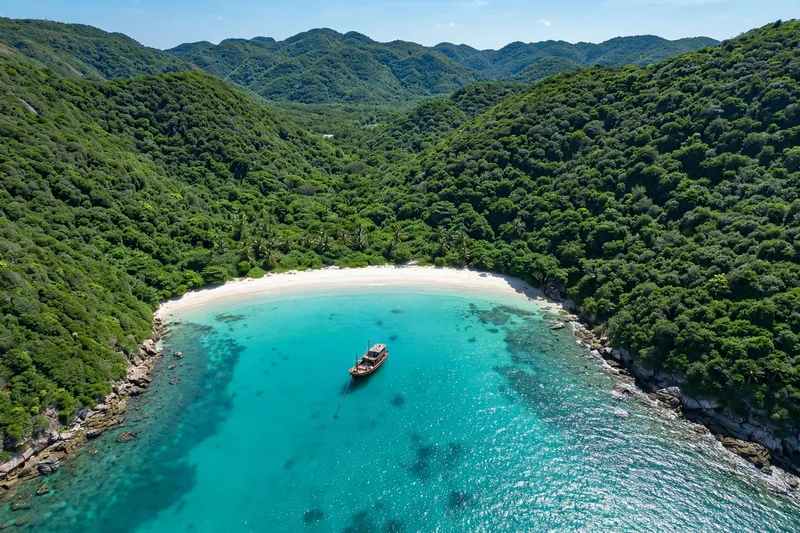Aerial view of a pristine Con Dao beach with turquoise water white sand and a wooden boat anchored offshore