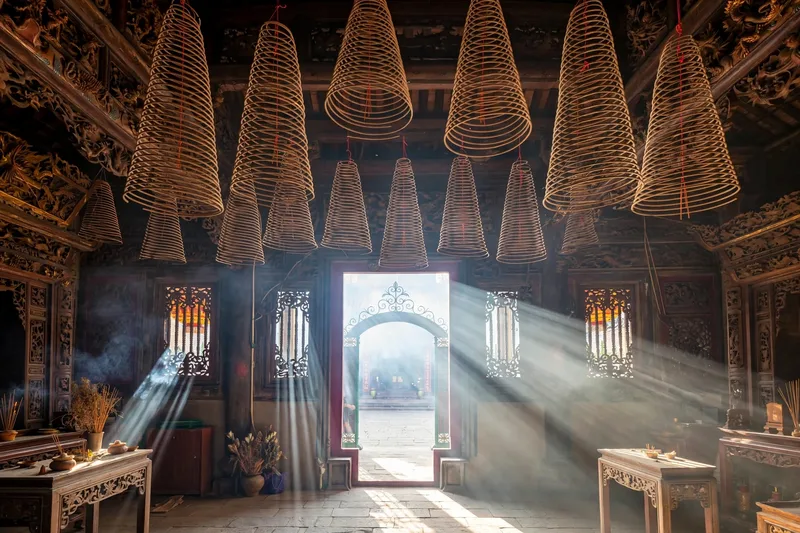 Incense coils hanging inside Thien Hau Temple in Cho Lon with sunlight streaming through the doorway