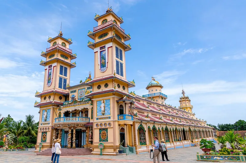 The colorful Cao Dai Holy See temple in Tay Ninh with ornate towers and dragon details under a blue sky