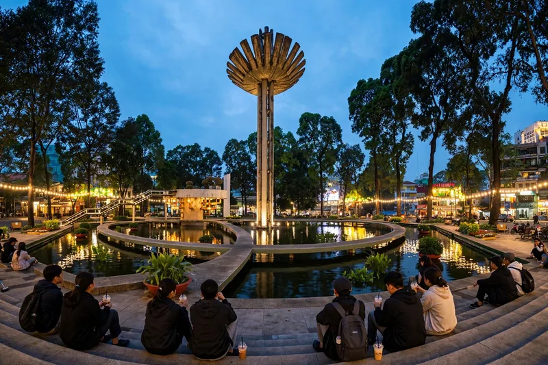 Young locals sitting around Turtle Lake in District 3 at dusk with the city skyline behind them